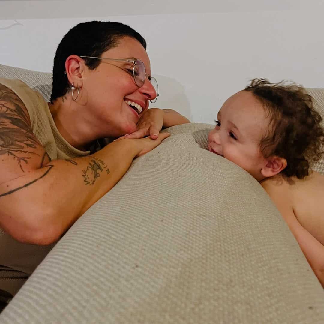 Happy mother and young child engaging in playful interaction on the sofa.